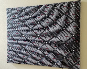 May include: Black fabric bulletin board with a diamond pattern and white "love" text repeated throughout. The board is covered in white pearl-like push pins.