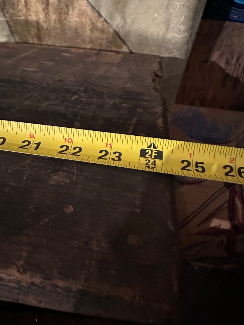 May include: A yellow measuring tape with black markings reads 21 to 26 inches. The tape is placed on a dark brown wooden surface.