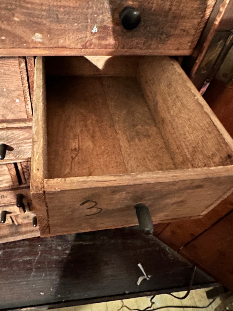May include: A wooden drawer with a black metal handle. The drawer is labeled with the number "3".