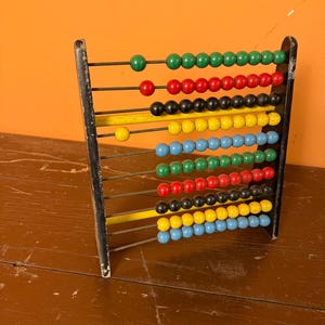 May include: A vintage abacus with a black frame and colorful wooden beads. The beads are arranged in rows of green, red, black, yellow, blue, and other colors. The abacus is a classic educational tool for learning math.