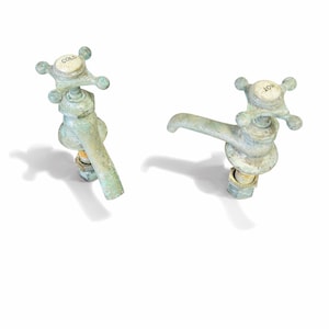May include: Two vintage water faucets with a weathered, aged appearance. One faucet is labeled "COLD", the other "HOT". The faucets have a cross-shaped handle and a spout. The metal has a greenish-blue patina.