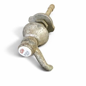 May include: A vintage metal soap dispenser with a push lever. The dispenser is silver with a white and red button that reads "SOAP PUSH". The dispenser has a curved spout and a textured surface.