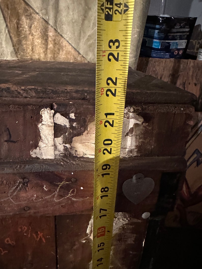May include: A yellow measuring tape with black markings is extended to 23 inches. The tape is attached to a wooden surface with a heart-shaped sticker.