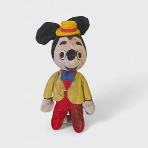 K&ouml;nnte beinhalten: Vintage Mickey Mouse Pl&uuml;schtier. Die Figur hat schwarze Ohren, einen gelben Hut mit rotem Band und eine gelbe Jacke &uuml;ber einer roten Weste. Sie hat rote Hosen, wei&szlig;e Handschuhe und eine blaue Fliege.