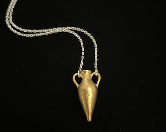 May include: A gold-colored necklace with a pendant shaped like a small, detailed amphora or ancient Greek vase.