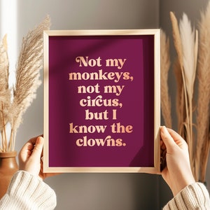 May include: A framed print with a burgundy background and rose gold text that reads "Not my monkeys, not my circus, but I know the clowns." The print is 8.5x11 inches and is printed on plum paper with rose gold foil.