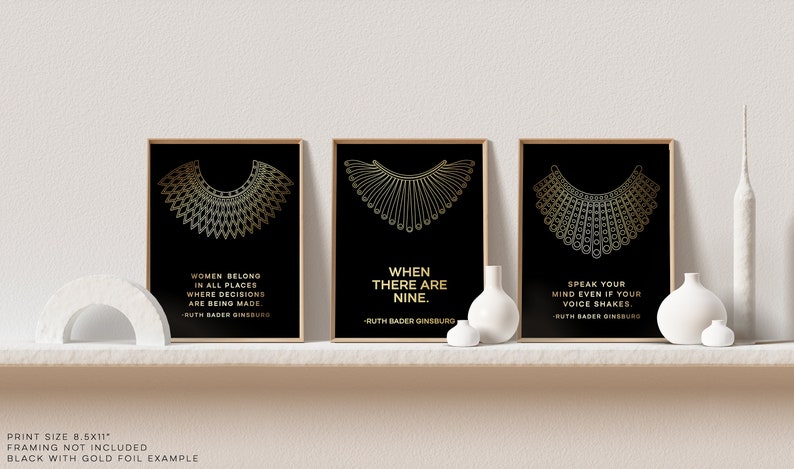 May include: Three black and gold framed prints with a quote from Ruth Bader Ginsburg on each. The quotes are "Women belong in all places where decisions are being made", "When there are nine." and "Speak your mind even if your voice shakes."
