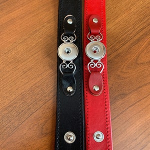 May include: Two leather bracelets, one black and one red, with silver snap closures and decorative accents. Each bracelet has multiple silver snaps and a decorative silver snap closure.