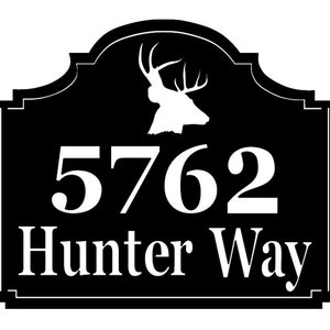 May include: Black rectangular address sign with white text and a deer silhouette. The sign reads "5762 Hunter Way" in a serif font. The deer silhouette is at the top of the sign.