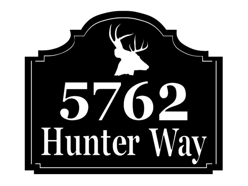 May include: Black rectangular address sign with white text and a deer silhouette. The sign reads "5762 Hunter Way" in a serif font. The deer silhouette is at the top of the sign.