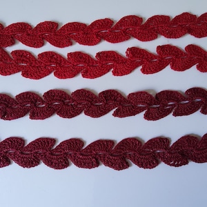 May include: Three rows of red and burgundy crocheted trim with a leaf pattern.