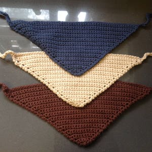 May include: Three crocheted triangle scarves in different colors: brown, beige, and blue. The scarves are layered on top of each other.