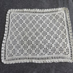 Puede incluir: Un encaje de ganchillo blanco con un delicado patrón floral. El encaje tiene un borde festoneado y está hecho con hilo fino.