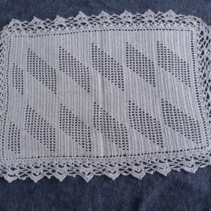 May include: A white crocheted doily with a delicate lace border and a repeating pattern of stylized leaves.