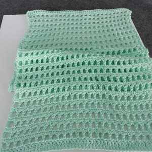 Könnte beinhalten: Eine hellgrüne Häkeldecke mit einem zarten Muster.