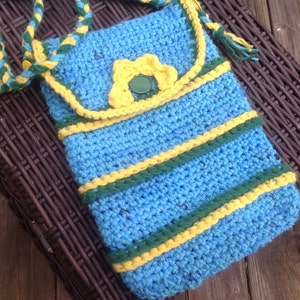 May include: A blue crocheted crossbody bag with yellow and green stripes. The bag has a flap with a yellow crocheted flower and a green button.