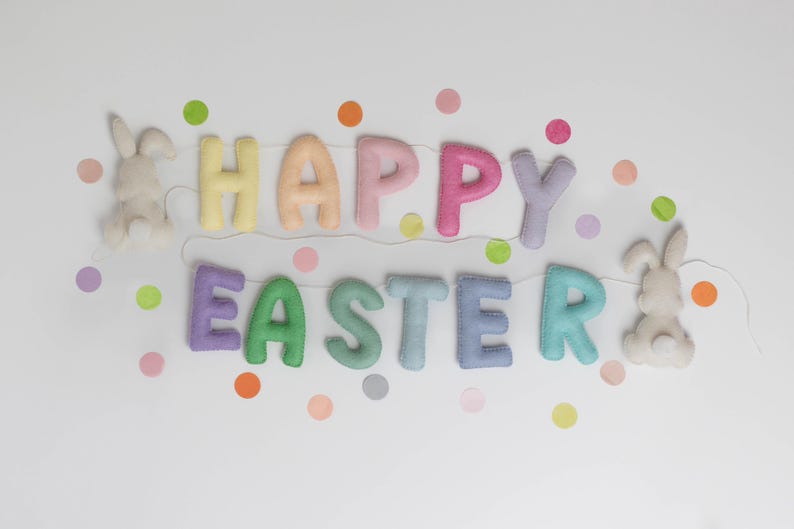 May include: A pastel-colored felt banner with the words "Happy Easter" and two white felt bunny rabbits on either end. The banner is decorated with colorful confetti dots.