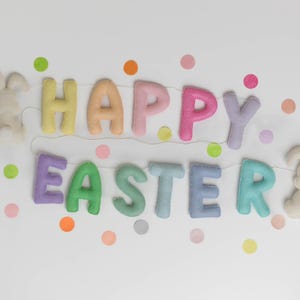 May include: A pastel colored felt banner that reads "Happy Easter" with two white felt bunny rabbits on either end. The banner is decorated with colorful confetti.