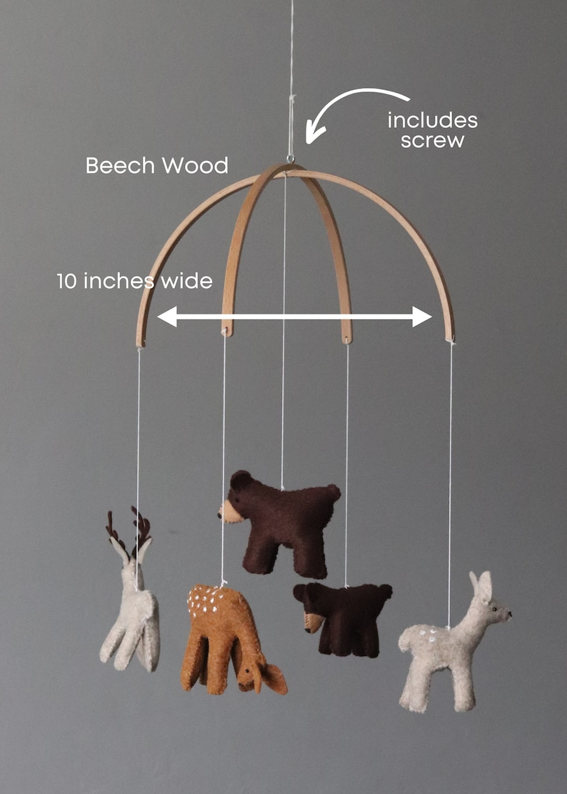 May include: A wooden mobile with a 10-inch wide beech wood frame. The mobile features five felt animal figures: two deer, two bears, and one fawn. The mobile includes a screw for hanging.