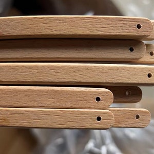 May include: Close-up of six unfinished wooden chair legs with holes drilled at the end of each leg.