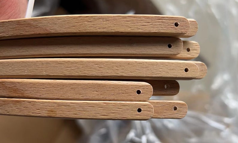 May include: Close-up of six unfinished wooden chair legs with holes drilled at the end of each leg.