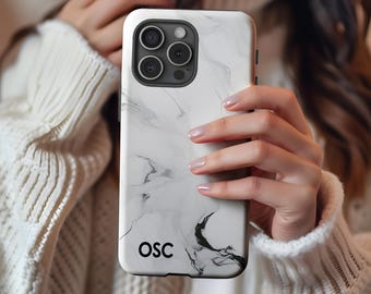 May include: White and gray marble-patterned phone case with black camera housing. The case features the initials "OSC" in black font. The design has a flowing, abstract pattern with dark gray and black accents. The phone case is held in a person's hands.