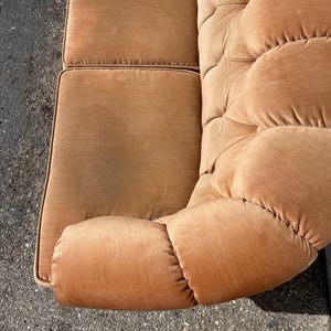 May include: A brown tufted velvet sofa with a curved armrest. The sofa has a classic design and is upholstered in a soft, plush fabric.