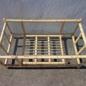 May include: A rectangular bamboo coffee table with a glass top. The table has a simple design with a woven bamboo base and a clear glass top.