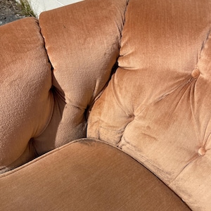 May include: A close-up of a brown tufted sofa with a button-tufted design. The sofa is made of a soft, plush fabric.