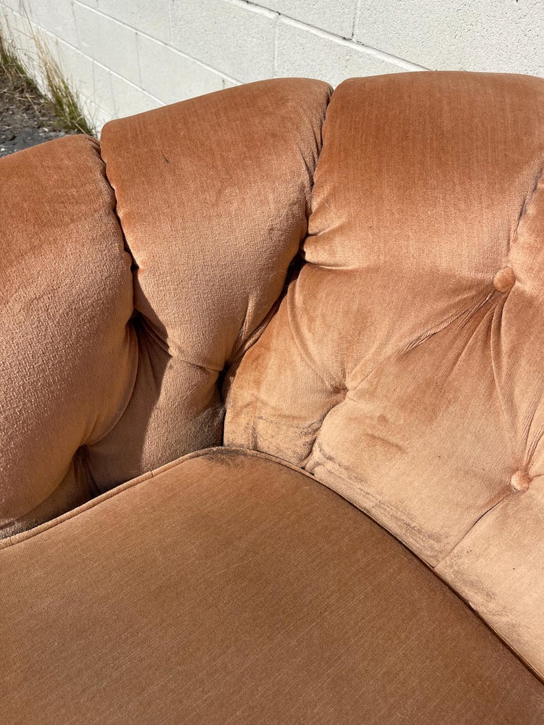 May include: A close-up of a brown tufted sofa with a button-tufted design. The sofa is made of a soft, plush fabric.