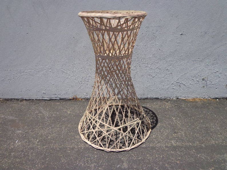 May include: White wicker end table with a round top and a woven design. The table has a unique, hourglass-shaped base.