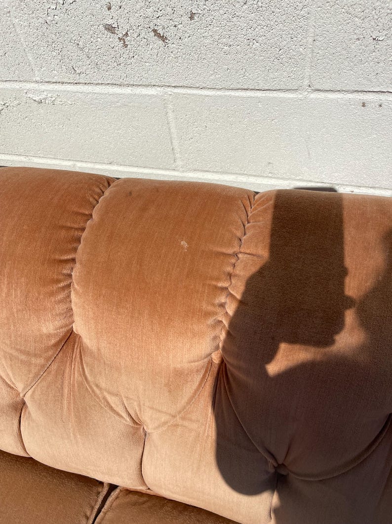 May include: A close-up of a brown tufted sofa with a shadow cast on the fabric.