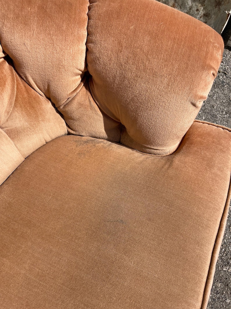 May include: A close-up of a brown velvet armchair with tufted upholstery. The fabric has a subtle sheen and a slightly worn appearance.