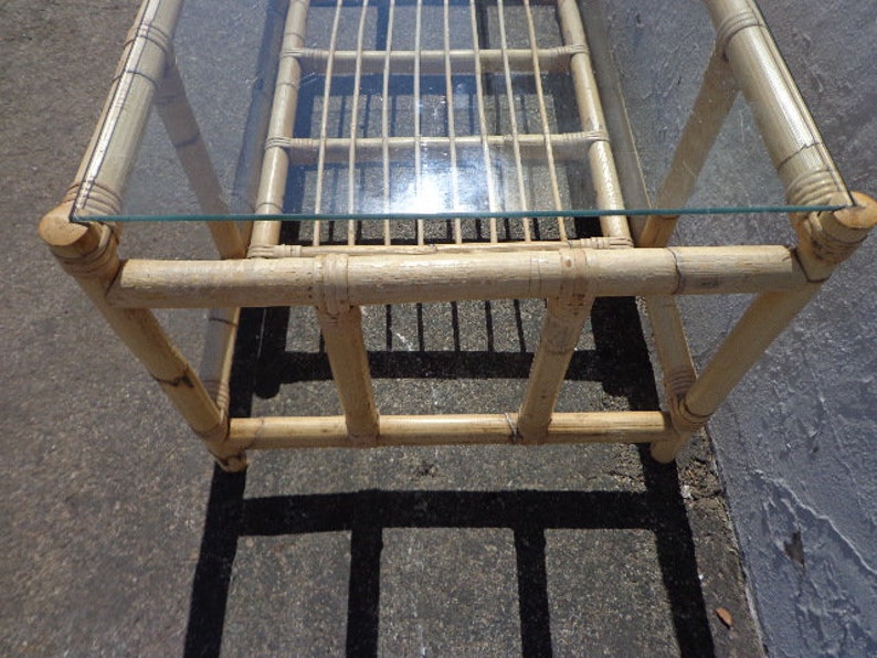 May include: A rectangular bamboo coffee table with a glass top. The table has a natural wood finish and is made of woven bamboo.