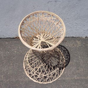 May include: A white wicker stool with a round seat and a woven design. The stool is made of natural materials and has a rustic look.