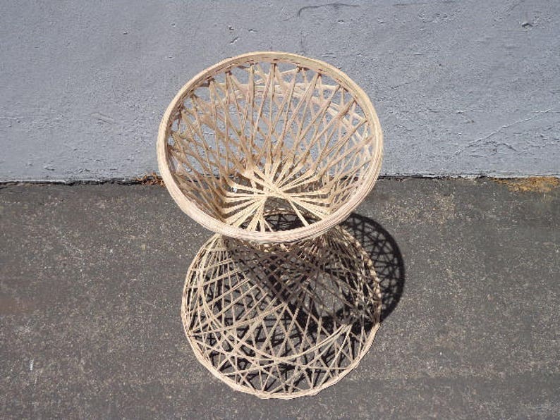 May include: A white wicker stool with a round seat and a woven design. The stool is made of natural materials and has a rustic look.