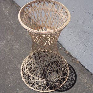 May include: A woven wicker lamp base with a wide, round top and a narrow, cylindrical base. The base is made of natural, light brown wicker and has a delicate, intricate pattern.