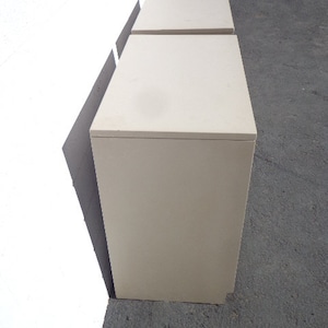 May include: Two off-white, rectangular, wooden nightstands with drawers. The nightstands are stacked on top of each other.