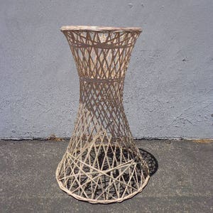 May include: A white wicker table with a round top and a flared base. The table is made of woven wicker and has a natural finish.