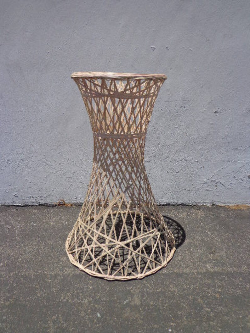 May include: A white wicker table with a round top and a flared base. The table is made of woven wicker and has a natural finish.