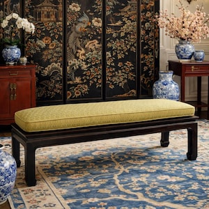 May include: A dark wood bench with a rectangular, light green patterned cushion. The bench is in front of a black screen with a floral and bird design. A blue floral rug is beneath the bench.