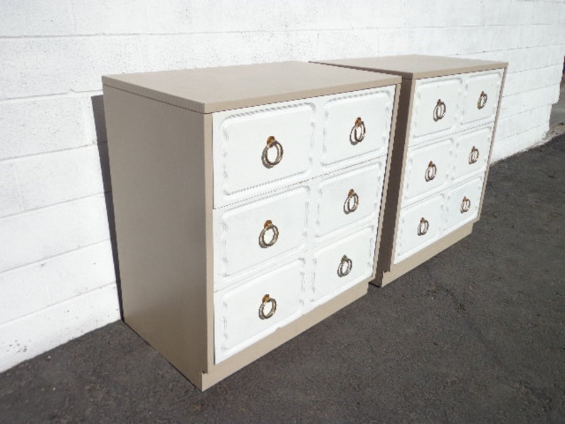 May include: Two white and beige dressers with gold ring pulls. Each dresser has five drawers.