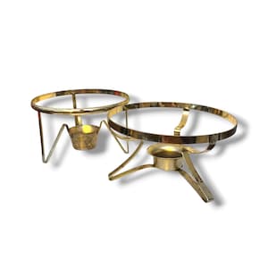 May include: Two gold-toned metal chafing dish stands, each featuring a circular top ring supported by three angled legs and a central circular holder designed to accommodate a heat source, showcasing a polished metallic finish throughout.