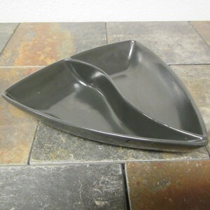 May include: A black ceramic triangular serving dish with two sections. The dish is made of a glossy material and has a modern design.