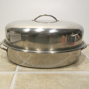 May include: A silver stainless steel roasting pan with a lid and two handles. The pan is oval shaped and has a shiny finish.