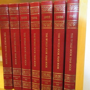 May include: A set of seven red hardcover books with gold lettering. The books are titled "The World Book Year Book" and each book features a different year from 1981 to 1987.
