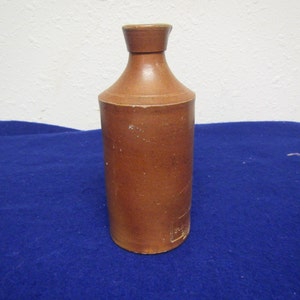 May include: A brown ceramic bottle with a narrow neck and a rounded body. The bottle has a smooth, glazed finish.