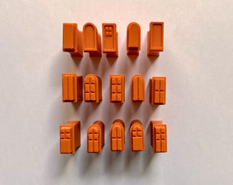 Könnte beinhalten: Orangefarbene Miniatur-Bausteine in verschiedenen Fenster- und Türdesigns. Die Blöcke sind in drei Reihen auf einer weißen Oberfläche angeordnet. Die Designs umfassen gewölbte, rechteckige und mehrteilige Fenster und Türen.