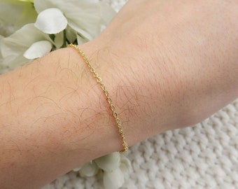 May include: A delicate gold chain bracelet on a person's wrist. The bracelet is simple and elegant, perfect for everyday wear.