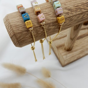 May include: Three adjustable bracelets with colorful beads that spell out the words "LOVE", "LIFE", and "JOY". Each bracelet has a gold chain and a sliding bead for adjusting the fit.
